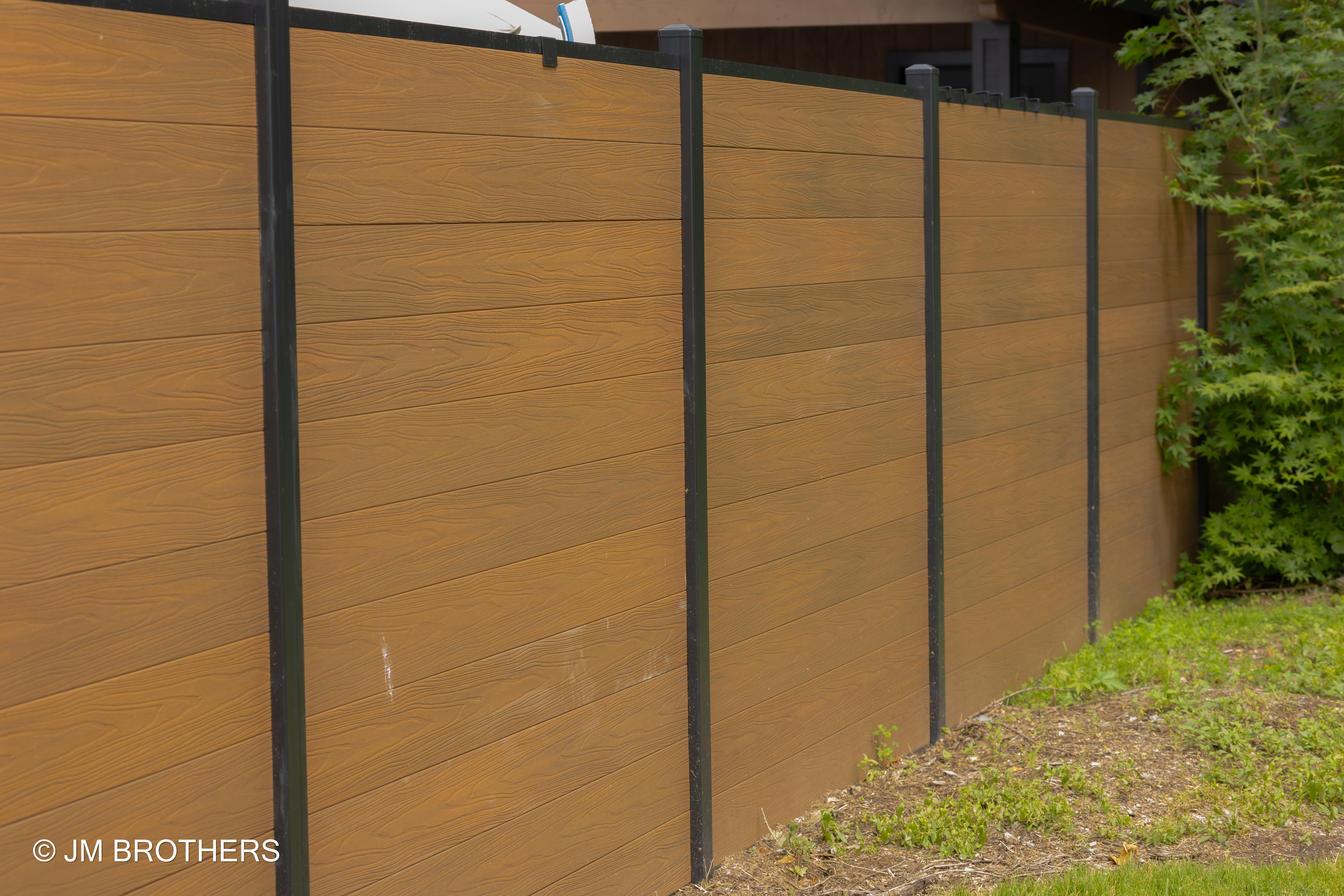 Beautiful modern home exterior featuring a sleek cedar-colored WPC composite fence
